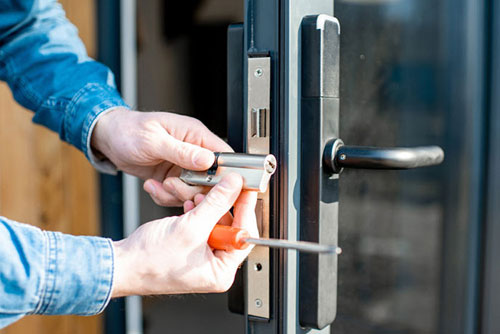 person with screwdriver repairing hinge in St. Charles